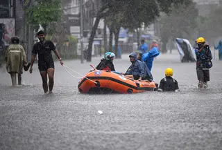 Warga setempat mengangkut tamu hotel menggunakan perahu karet melalui jalan yang tergenang air akibat banjir setelah hujan lebat di Legian Kuta, Denpasar, Bali, pada Selasa 24 Februari 2026. Banjir kembali melanda sejumlah kawasan di pulau Dewata. (SONNY TUMBELAKA/AFP)