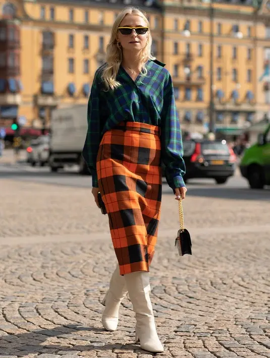 Atau padukan atasan flanel dengan motif kotak-kotak. Untuk menghindari kesan pola yang berlebihan, gunakan aksesori berwarna solid dengan nada netral, seperti boots putih dan handbag hitam yang sederhana. Foto: Purewow.
