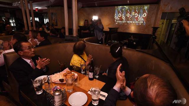 Warga Korea di Los Angeles menyaksikan momen bersejarah pertemuan Donald Trump dan Kim Jong-un di Singapura. (AFP/Robyn Beck)