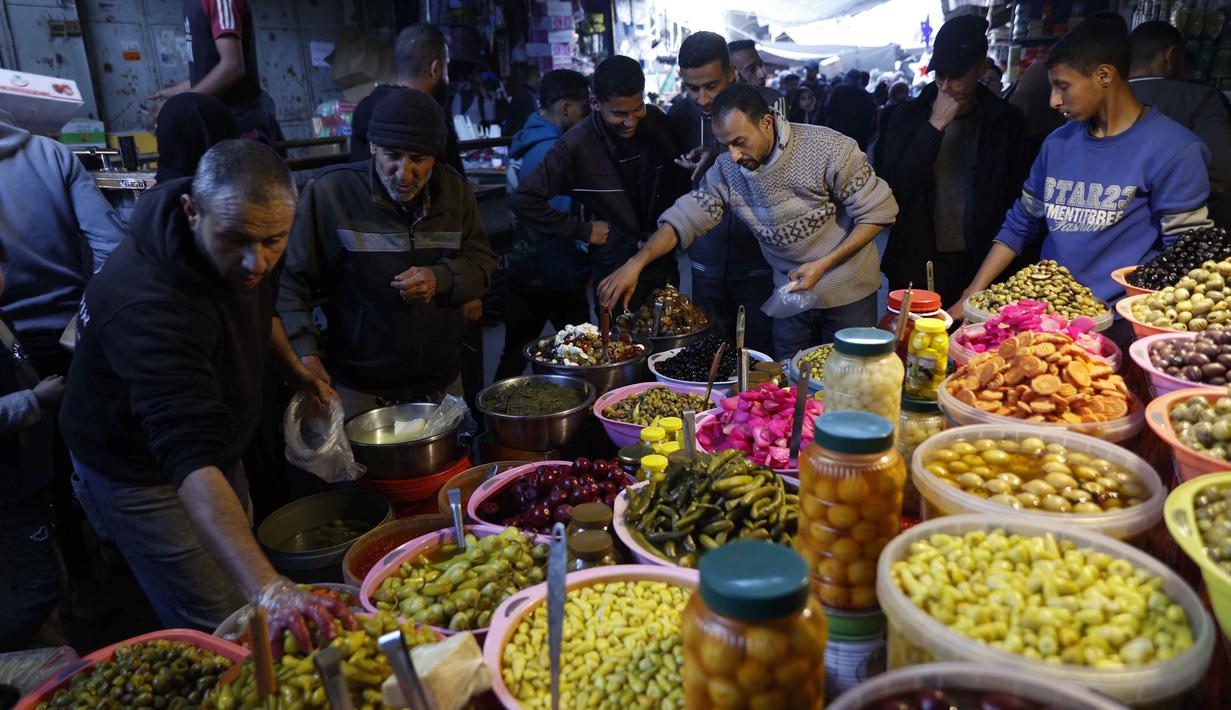 Mereka membeli berbagai kebutuhan pokok dan hidangan tradisional khas Ramadan. Tampak dalam foto, warga Palestina berbelanja acar di pasar Zawiya, Kota Gaza, pada Rabu 18 Februari 2026. (Omar AL-QATTAA/AFP)