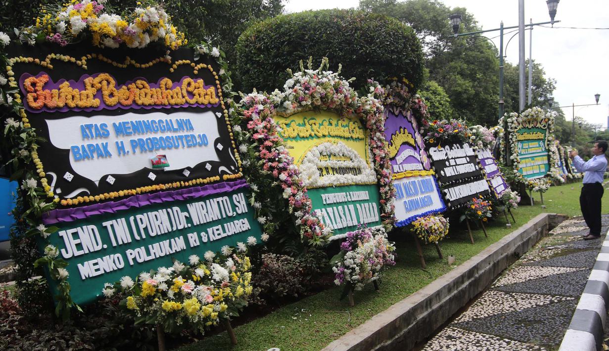 Warga mengambil gambar karangan bunga ucapan duka cita untuk Probosutedjo yang memenuhi Jalan Diponegoro, Jakarta, Senin (26/3). Salah satu karangan bunga bertuliskan dari Menko Polhukam RI Wiranto. (Liputan6.com/Arya Manggala)