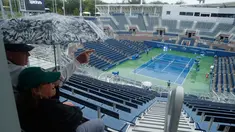 Penonton duduk menunggu penundaan pertandingan akibat hujan selama putaran pertama turnamen tenis AS Terbuka 2017 di Grandstand Stadium, New York (29/8). Meski hujan, para penonton tetap antusias. (AP Photo / Andres Kudacki)