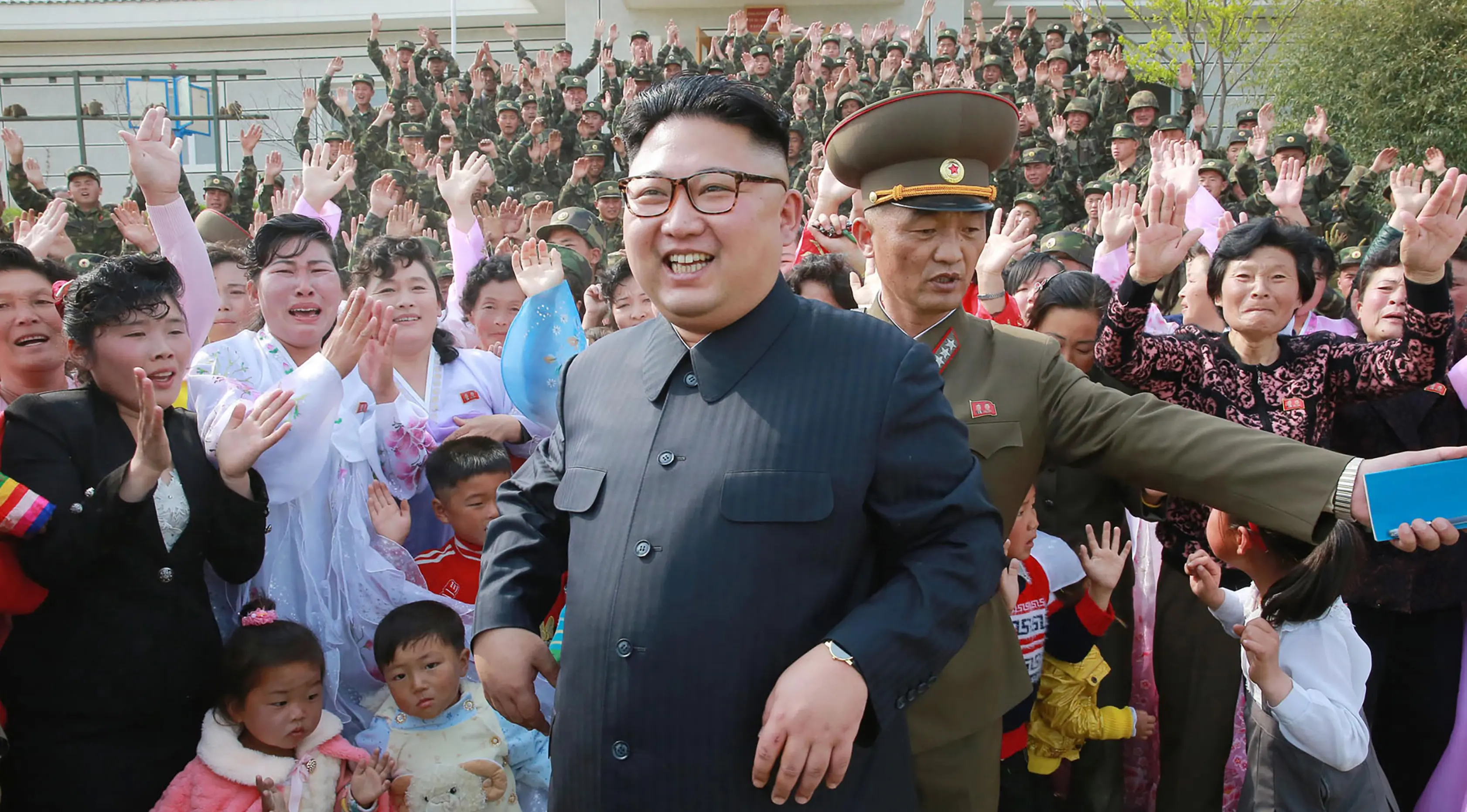 Warga dan tentara Korea Utara menyambut kedatangan pemimpin mereka, Kim Jong-un yang sedang mengecek detasemen pertahanan di Pulau Jangjae dan Detasemen Pertahanan Pahlawan di Mu Islet, Korea Utara (5/5). (STR / KCNA VIA KNS / AFP)