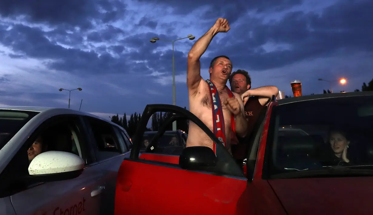 Para suporter bersorak saat menyaksikan pertandingan Viktoria Plzen dan Sparta Praha di sebuah bioskop drive-in di Pilsen, Republik Ceko, Rabu (27/5/2020). Di tengah pandemi COVID-19, suporter Ceko dapat menyaksikan pertandingan bola lewat layar di bioskop drive-in. (AP Photo/Petr David Josek)