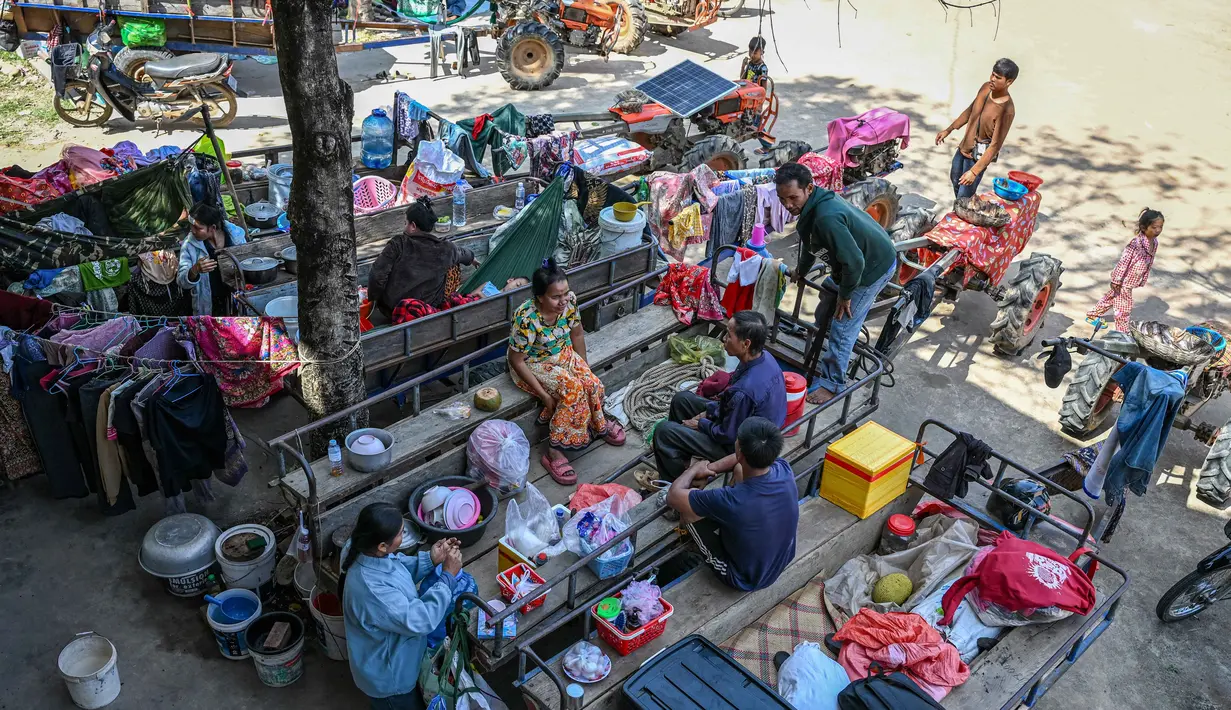 Sementara itu, puluhan ribu orang telah meninggalkan rumah mereka di dekat perbatasan untuk mencari tempat penampungan yang aman. Tampak dalam foto, warga berkumpul di luar sebuah kuil setelah dievakuasi menyusul bentrokan di sepanjang perbatasan Kamboja-Thailand, di provinsi Siem Reap pada Selasa 9 Desember 2025. (TANG CHHIN SOTHY/AFP)