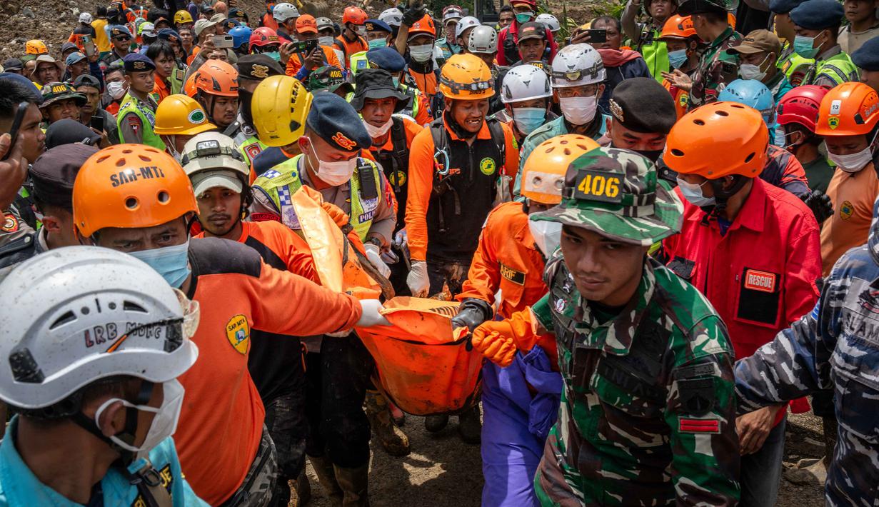 Tim gabungan dari berbagai unsur (termasuk TNI dan BPBD) mengerahkan alat berat seperti ekskavator untuk membantu pencarian di area yang aman. Tampak dalam foto, petugas penyelamat membawa korban dalam operasi penacarian di lokasi longsor di Desa Situkung, Banjarnegara, Jawa Tengah, pada Kamis 20 November 2025. (DEVI RAHMAN/AFP)