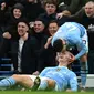 Striker Man City, Erling Haaland (bawah), bersama Phil Foden, merayakan gol yang dicetaknya ke gawang Manchester United (MU) dalam laga pekan ke-27 Liga Inggris 2023/2204 di Etihad Stadium, Minggu (3/3/2024) malam WIB. (Paul ELLIS / AFP)