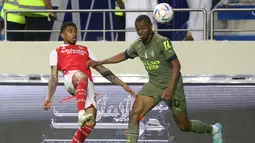 Gelandang Arsenal, Reiss Nelson berebut bola dengan bek AC Milam, Pierre Kalulu selama pertandingan Dubai Super Cup 2022 di di stadion al-Maktoum di Uni Emirat Arab (13/12/2022). Arsenal menang tipis atas AC Milan dengan skor 2-1. (AFP/Karim Sahib)