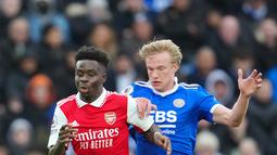 Pemain Arsenal Bukayo Saka (kiri) memperebutkan bola dengan pemain Leicester City Victor Kristiansen pada pertandingan sepak bola Liga Inggris di The King Power Stadium, Leicester, Inggris, 25 Februari 2023. Arsenal mengalahkan Leicester City dengan skor 1-0. (AP Photo/Jon Super)