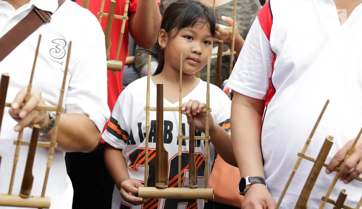 Seorang anak memainkan angklung saat meramaikan acara 'Bangkit Indonesia' di Lokasi Car Free Day (CFD), Jakarta, Minggu (21/5). Acara memperingati Hari Kebangkitan Nasional itu dirayakan dengan pembagian 1.500 angklung. (Liputan6.com/Immanuel Antonius)