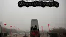 Kabut asap menyelimuti Lapangan Tiananmen, Beijing, Rabu (15/1/2015). Seorang pria berdiri di atas panggung saat berpose dekat menara observatorium di Beijing. (REUTERS/Kim Kyung-Hoon)