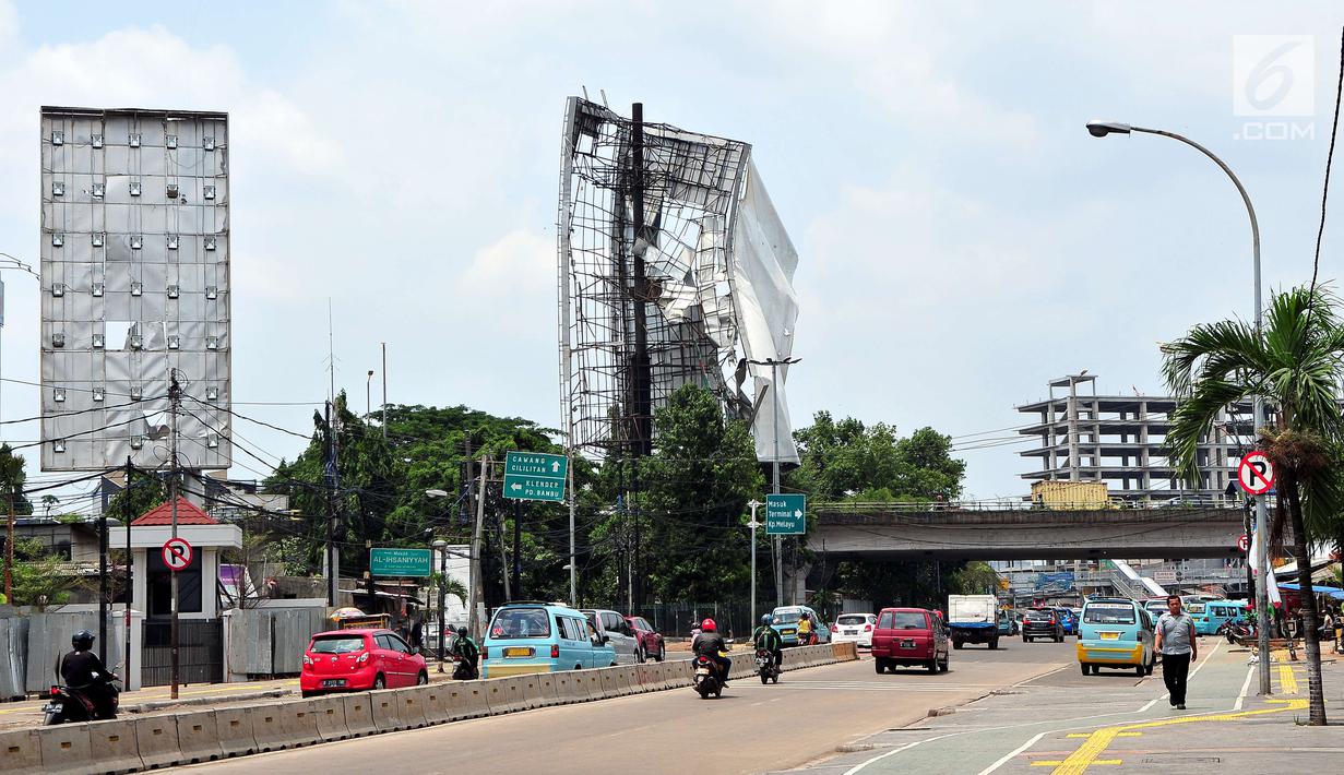 Sejumlah pengendara melintas di dekat papan reklame yang hampir roboh di kawasan Terminal Kampung Melayu, Jakarta (2/10). Hujan deras disertai angin kencang yang mengguyur Ibu Kota kemarin membuat papan reklame ini hampir roboh.(Liputan6.com/Helmi Afandi)