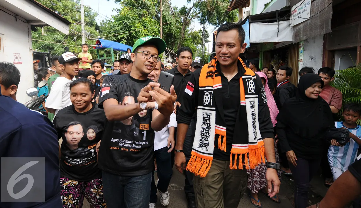 Cagub DKI Jakarta, Agus Harimurti Yudhoyono (kanan) berjalan saat sosialisasi di Jalan Menteng Raya, Jakarta, Kamis (22/12). Sebelumnya, Agus berkeliling ke beberapa RW di kawasan Menteng Tenggulun, Jakarta. (Liputan6.com/Helmi Fithriansyah)