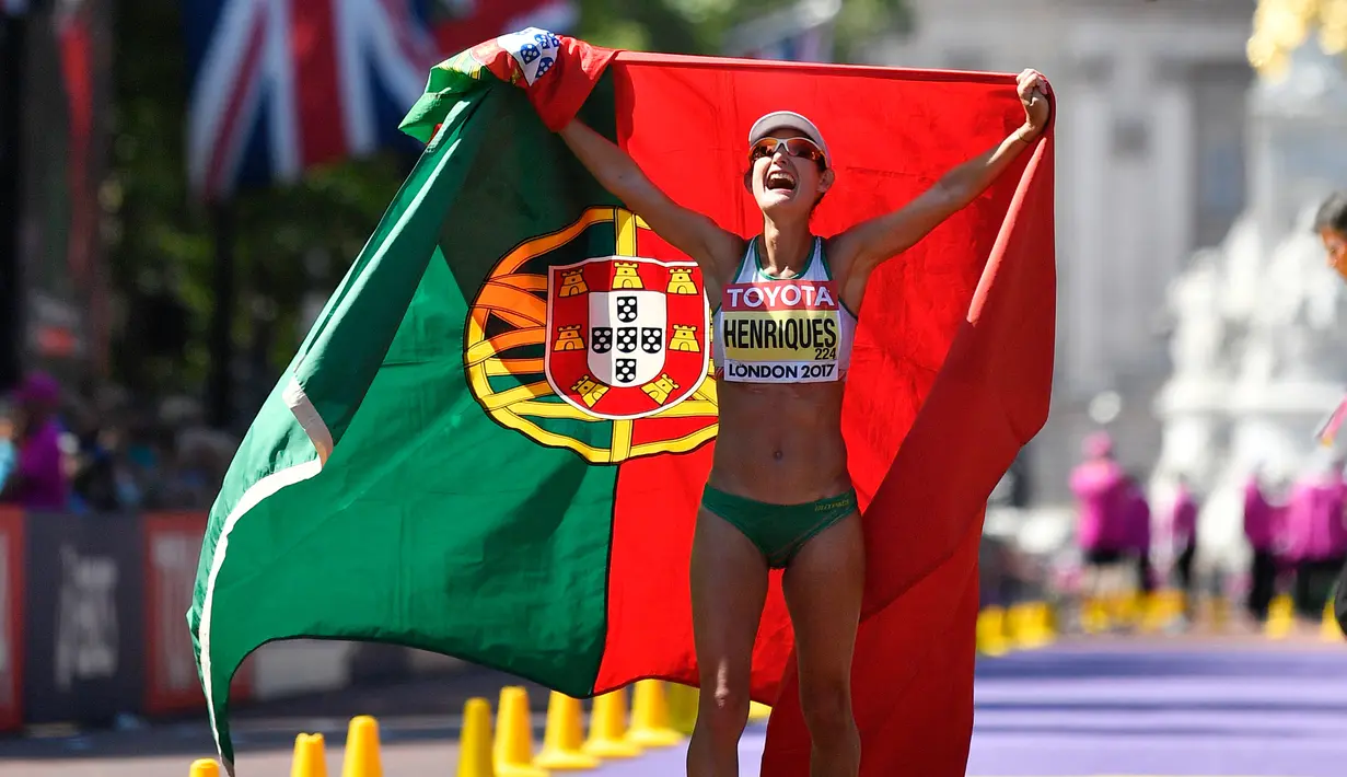 Pelari putri asal Portugal, Ines Henriques melakukan selebrasi membentangkan bendera negaranya setelah memenangkan medali emas dalam lomba lari putri selama Kejuaraan Atletik Dunia di London, Inggris (13/8). (AP Photo / Martin Meissner)
