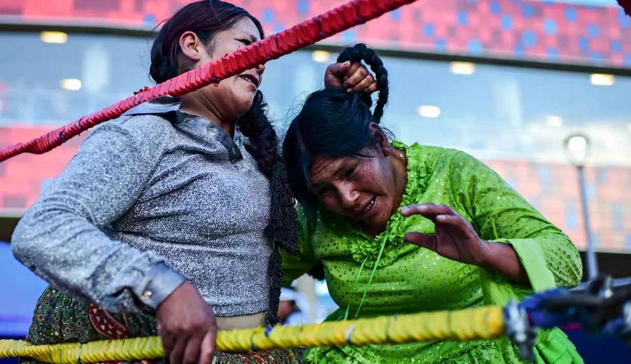 Pegulat Bolivia Ana Luisa Yujra (kiri), bertarung dengan lawannya, Lidia Flores, di atas ring gulat di El Alto, pada 24 November 2019. Di Bolivia ada sebuah atraksi gulat yang diperankan perempuan dengan menggunakan busana khas warga Bolivia. (Ronaldo SCHEMIDT / AFP)