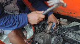 Pekerja memisahkan mesin dari kerangka bajaj. Rencananya bajaj orange akan dimusnahkan dan diganti Bajaj biru berbahan bakar gas (BBG), Jakarta, Rabu (4/3/2015). (Liputan6.com/Herman Zakharia)