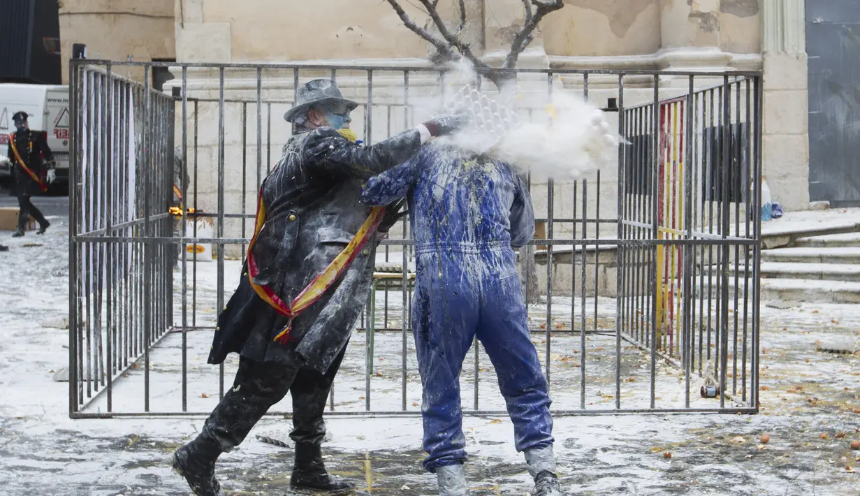 Seorang pria menaburkan tepung ke arah lawannya saat Festival Els Enfarinats di kota Ibi, Spanyol, Rabu (28/12). Festival tahunan Els Enfarinats memang selalu dirayakan dengan perang tepung dan telur. (AFP PHOTO / Jamie Reina)