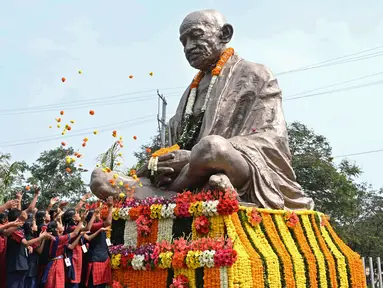 Sejumlah siswa sekolah menaburkan bunga pada patung Mahatma Gandhi pada hari peringatan kematiannya di Hyderabad, India, Senin (30/1/2023). Pada 30 Januari 1948, pemimpin spiritual dan gerakan politik kemerdekaan India Mahatma Gandhi tewas terbunuh. Mahatma Gandhi tewas ditembak oleh seorang ekstremis Hindu Nathuram Godse. (NOAH SEELAM/AFP)