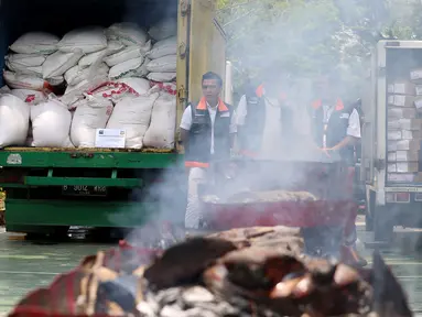 Petugas dari Kementerian Perdagangan memusnakan gula kristal dan daging beku yang sudah kedaluwarsa hasil sitaan dari pasar dengan cara di bakar, di Lapangan Parkir Kemendag, Jakarta Kamis (28/9). (Liputan6.com/JohanTallo)