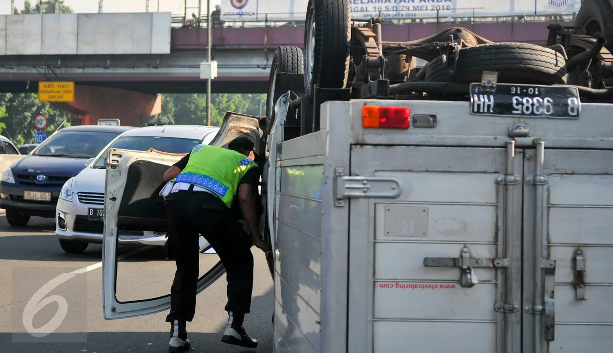 Seorang petugas jalan tol memeriksa mobil boks yang terbalik di KM 02 Tol Cawang arah Cililitan, Jakarta, Senin (30/5). Akibat kecelakaan itu arus lalu lintas terpantau padat sepanjang 2 kilometer. (Liputan6.com/Yoppy Renato)