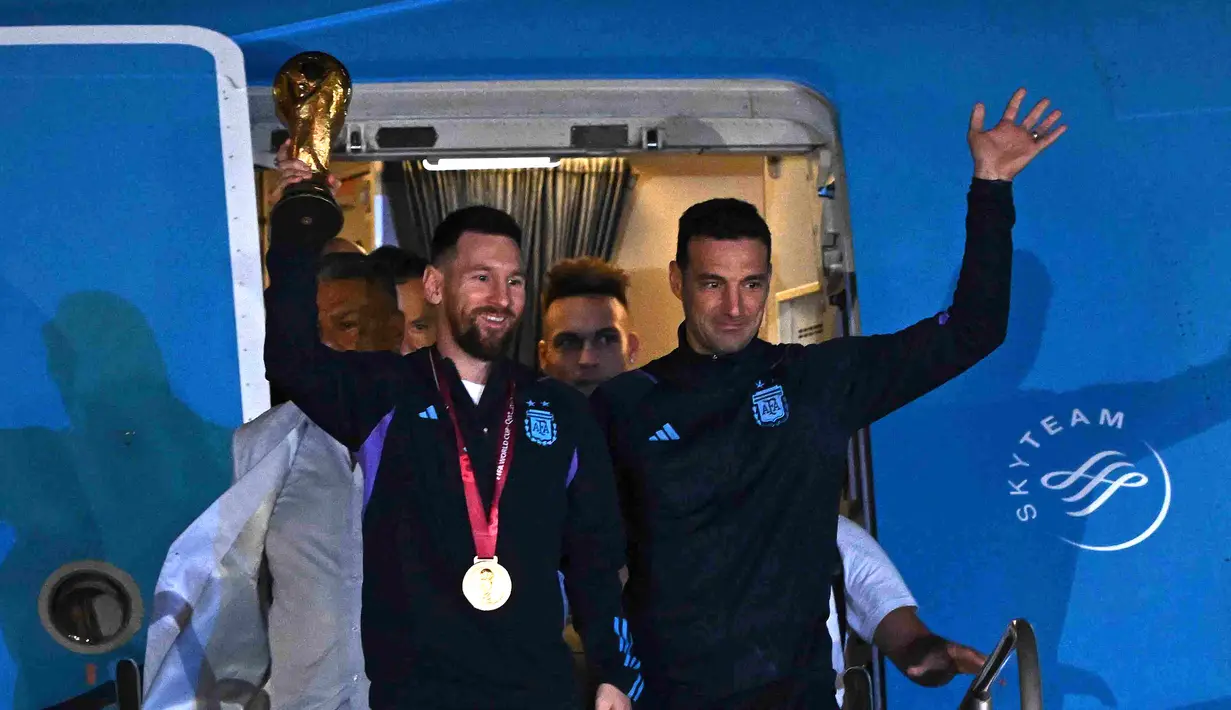 Kapten Argentina Lionel Messi (kiri) memegang Trofi Piala Dunia 2022 bersama pelatih Lionel Scaloni saat turun dari pesawat setibanya di Bandara Internasional di Ezeiza, provinsi Buenos Aires, Argentina (20/12/2022). Argentina tampil sebagai juara Piala Dunia 2022 setelah menumpas Prancis melalui adu penalti di final. (AFP/Luis Robayo)