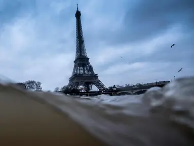 Menara Eiffel terlihat saat sungai Seine di Paris meluap, Prancis (7/1). Sungai Seine tidak mampu menampung debit air setelah hujan terjadi terus-menerus sehingga meluap sejajar dengan tinggi jalan. (AFP Photo/Olivier Morin)