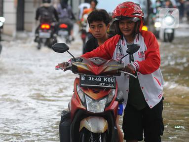 Pengendara mendorong motornya melintasi banjir di Jalan Benteng,  Duta Kranji, Kalibaru, Bekasi, Jawa Barat, Jumat (24/2/2023). Hujan yang turun di Bekasi sejak Kamis malam mengakibatkan sejumlah wilayah di Bekasi tergenang hingga lebih dari 50 cm. (merdeka.com/Imam Buhori)