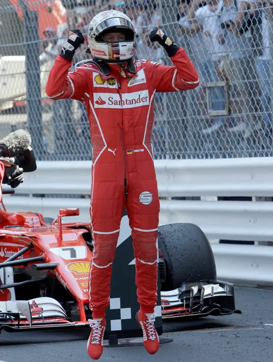 Pembalap Ferrari, Sebastian Vettel melakukan selebrasi setelah finis urutan pertama pada balapan GP Monaco di Sirkuit Monte Carlo, Minggu (28/5). Bagi Ferrari, ini merupakan kemenangan pertama mereka di Monaco sejak 2001. (AP Photo/Claude Paris)