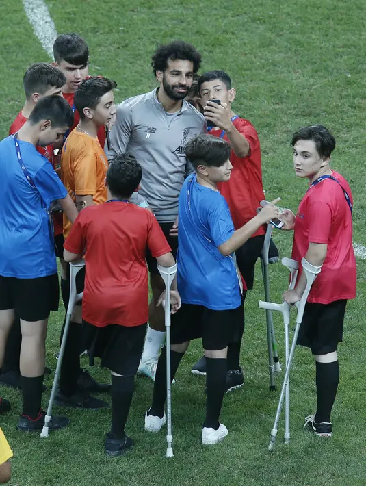 Gelandang Liverpool, Mohamed Salah foto bersama anak-anak selama sesi latihan jelang bertanding melawan Chelsea pada Piala Super Eropa 2019 di Stadion Taman Besiktas, di Istanbul (13/8/2019). (AP Photo/Lefteris Pitarakis)