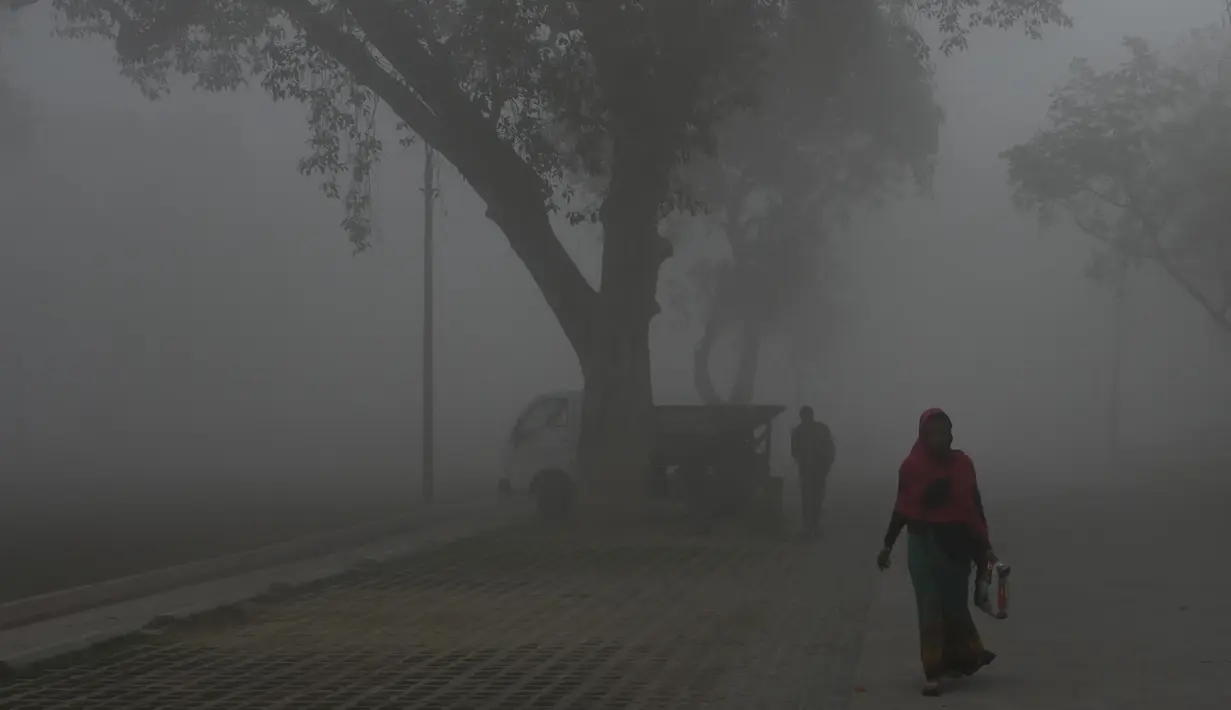 Orang-orang berjalan di sepanjang jalan di dekat gerbang India di tengah kabut asap tebal di New Delhi pada Rabu (22/2/2023). Pada 2020 lalu, platform pengukur tingkat kualitas udara yang bermarkas di Swiss, IQAir mengungkapkan New Delhi merupakan ibu kota paling berpolusi dalam kurun tiga tahun berturut-turut. Tak cuma ibu kota negara, bahkan dari 50 kota paling berpolusi di dunia, 35 di antaranya ada di India. (Arun SANKAR/AFP)