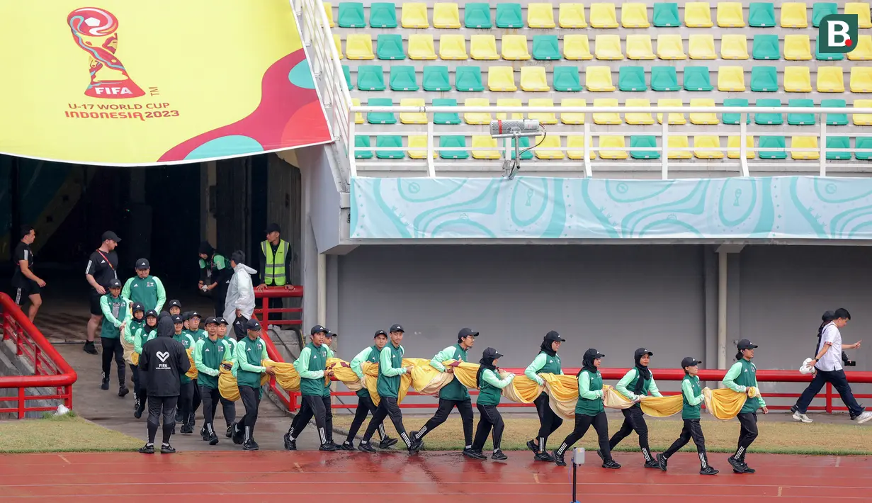 Sejumlah petugas membawa bendera untuk dibentangkan di tengah lapangan sebelum laga Piala Dunia U-17 2023 antara Timnas Mali U-17 melawan Timnas Kanada U-17 di Stadion Gelora Bung Tomo (GBT), Surabaya, Kamis (16/11/2023). (Bola.com/Bagaskara Lazuardi)