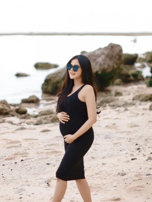 Penampilan Bella makin sempurna dengan kaca mata hitam yang dikenakan. Pose memegang baby bump yang makin besar. [Instagram/bellabonita_r.a]