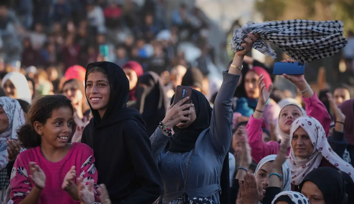 Acara yang dihadiri ratusan warga dan dimeriahkan dengan musik serta tarian tradisional itu menghidupkan kembali suasana yang selama ini dipenuhi kesedihan. Tampak dalam foto, warga Palestina menyaksikan dan merayakan upacara pernikahan massal di Kota Hamad, Khan Younis, Jalur Gaza, Selasa 2 Desember 2025. (AP Photo/Abdel Kareem Hana)