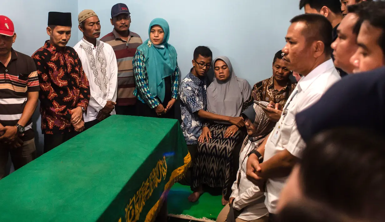 Orangtua (tengah dan kanan) bersama anggota keluarga berkumpul dekat peti mati  jenazah korban jatuhnya pesawat Lion Air JT 610 Jannatun Cintya Dewi sebelum pemakaman di kediaman kawasan Sukodono, Sidoarjo, Jawa Timur, Kamis (1/11). (JUNI KRISWANTO / AFP)