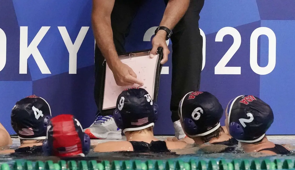 Pemain polo air Amerika Serikat mendengarkan pelatih kepala Adam Krikorian saat waktu istirahat dalam pertandingan babak penyisihan polo air putri Olimpiade Tokyo 2020 melawan Hungaria, Rabu (28/7/2021). (Foto: AP/Mark Humphrey)