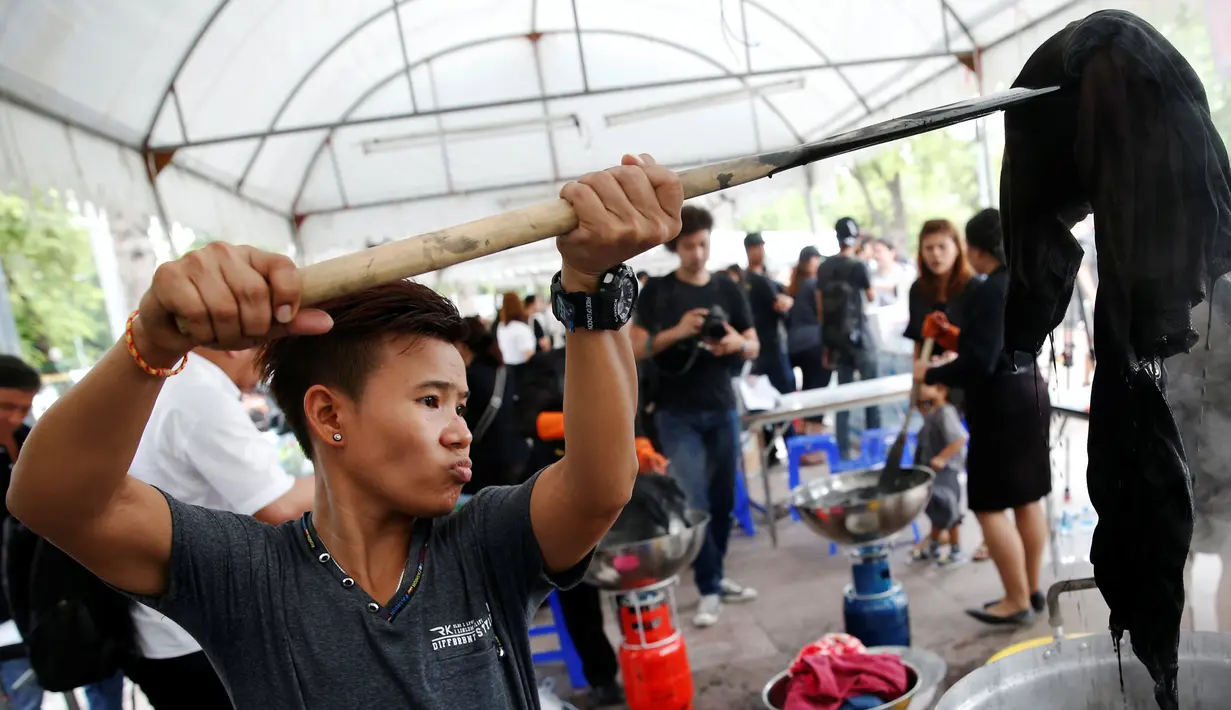 Seorang relawan sedang mewarnai pakaian agar menjadi hitam di Grand Palace di Bangkok, Thailand (17/10). Selama masa berkabung wafatnya raja Bhumibol Adulyadej warga Thailand mengenakan pakaian berwarna hitam.(Reuters/Edgar Su)