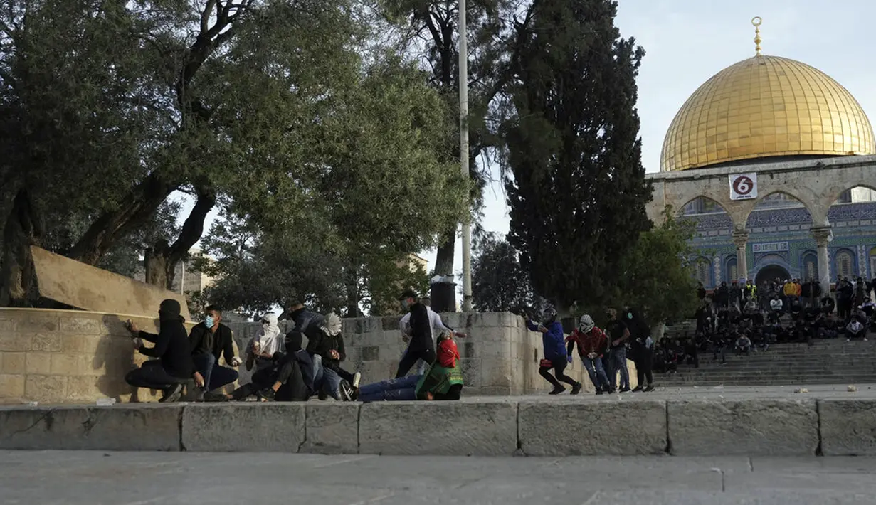 <p>Pengunjuk rasa Palestina berlindung saat mereka bentrok dengan polisi Israel di Kompleks Masjid Al Aqsa, Yerusalem, Jumat (22/4/2022). Polisi Israel dan pemuda Palestina kembali bentrok di Kompleks Masjid Al Aqsa. (AP Photo/Mahmoud Illean)</p>