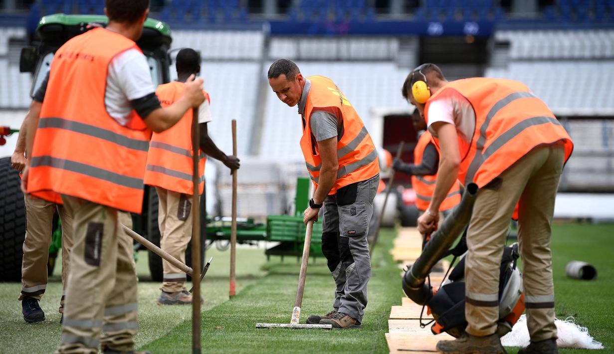 Sejumlah pekerja sedang memasang rumput hybrid baru di Stade de France, Saint-Denis, pada 24 Mei 2022 waktu setempat. Dalam waktu 48 jam, rumput baru yang ditanam di luar Barcelona, dipasang di Stade de France untuk pertandingan final Liga Champions antara Real Madrid dan Liverpool yang dijadwalkan berlangsung pada 28 Mei 2022. (AFP/Franck Fife)