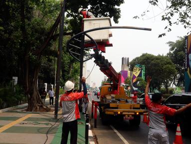 Petugas Suku Dinas PE Jakarta Pusat bersama Satgas PJU, mencabut dan menggeser tiang listrik dan lampu penerangan jalan yang menghalangi jalur sepeda di trotoar Jalan Asia Afrika dan Jalan Gelora, Senayan, Jakarta, Rabu (1/8). (Liputan6.com/Johan Tallo)