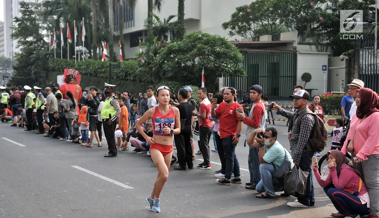 Warga menyaksikan lomba lari maraton putri Asian Games 2018 di kawasan MH Thamrin, Jakarta, Minggu (26/8). Meski Car Free Day ditiadakan, warga Ibu Kota tetap memadati kawasan MH Thamrin menyaksikan maraton Asian Games 2018. (Merdeka.com/Iqbal S. Nugroho)