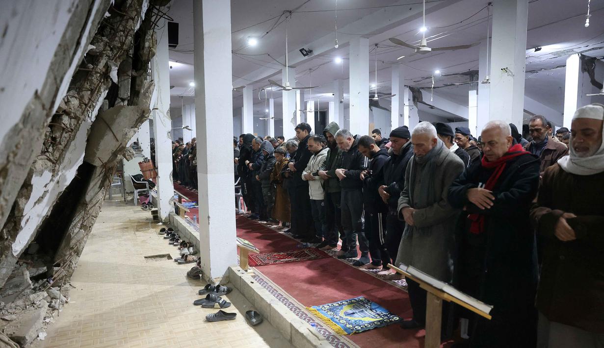 Kesemua amalan tersebut bertujuan untuk meraih kemuliaan malam Lailatul Qadar, yang nilainya lebih baik dari seribu bulan. Tampak dalam foto, umat Muslim melaksanakan salat malam di Masjid Mahaba yang rusak selama perang Israel-Hamas di Khan Yunis, Jalur Gaza selatan pada Senin 16 Maret 2026. (Bashar Taleb/AFP)
