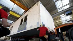 Pegawai bangunan saat merekonstruksi sebuah rumah prefabrikasi untuk pengungsi di perusahaan konstruksi Bauer Holzsysteme, Jerman, (7/12).  Rumah prefabrikasi ini dapat diangkut dan dipindahkan dengan menggunakan truk angkut. (REUTERS/Michaela Rehle)