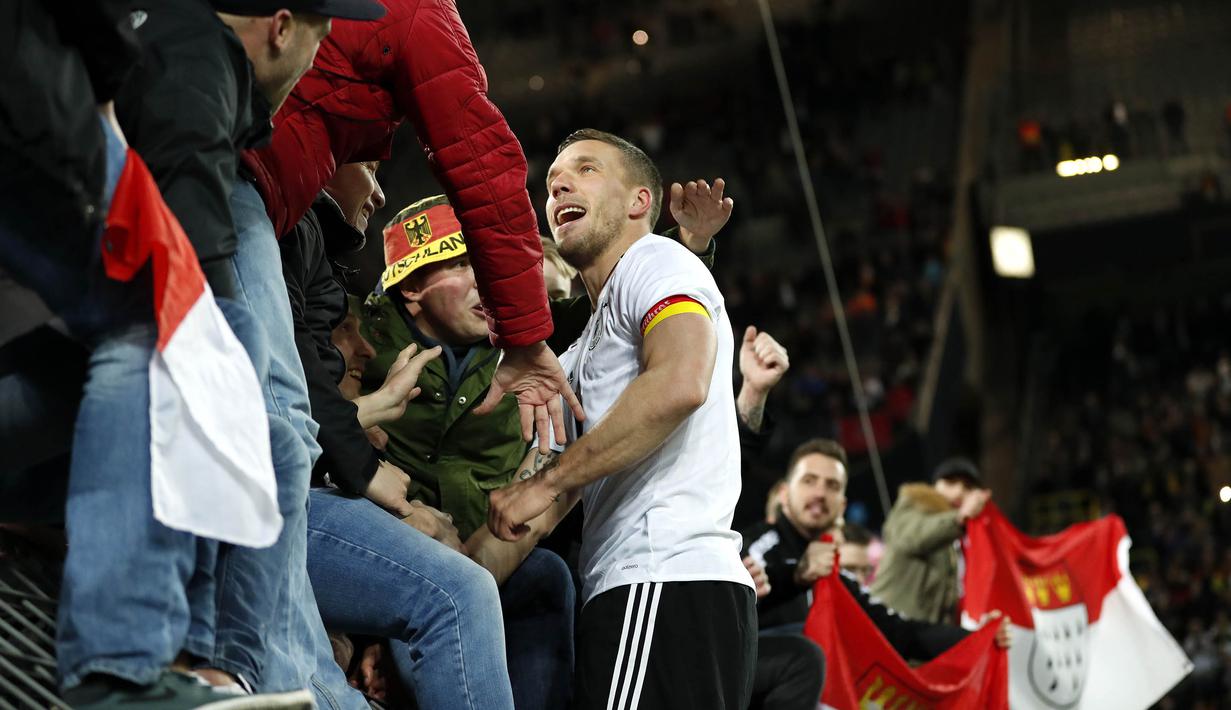 Gelandang Jerman, Lukas Podolski, menghampiri suporter usai mencetak gol ke gawang Inggris. Podolski mampu tampil sebagai bintang di laga terakhirnya berseragam timnas Jerman. (EPA/Friedemann Vogel)