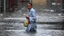 Seorang pria menyeberangi jalan yang tergenang air saat hujan monsun lebat di Rawalpindi, Pakistan, pada 17 Juli 2025. (Aamir Qureshi/AFP)