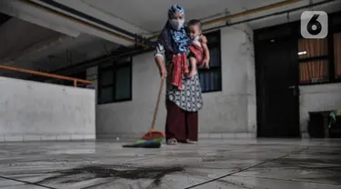 Warga saat menyapu debu batu bara yang mengotori depan rumahnya di Rusunawa Marunda, Jakarta Utara, Rabu (9/3/2022). Menurut warga rusun, pencemaran debu batu bara sudah berlangsung sejak 2019. (merdeka.com/Iqbal S. Nugroho)