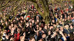 Para peserta berebut bola dekat pohon saat mengikuti Royal Shrovetide Football Match di Ashbourne, Derbyshire, Inggris, Selasa (5/3). Pertandingan ini mempertemukan orang-orang yang terpisah oleh Sungai Derwent di kota tersebut. (Oli Scarff/AFP)