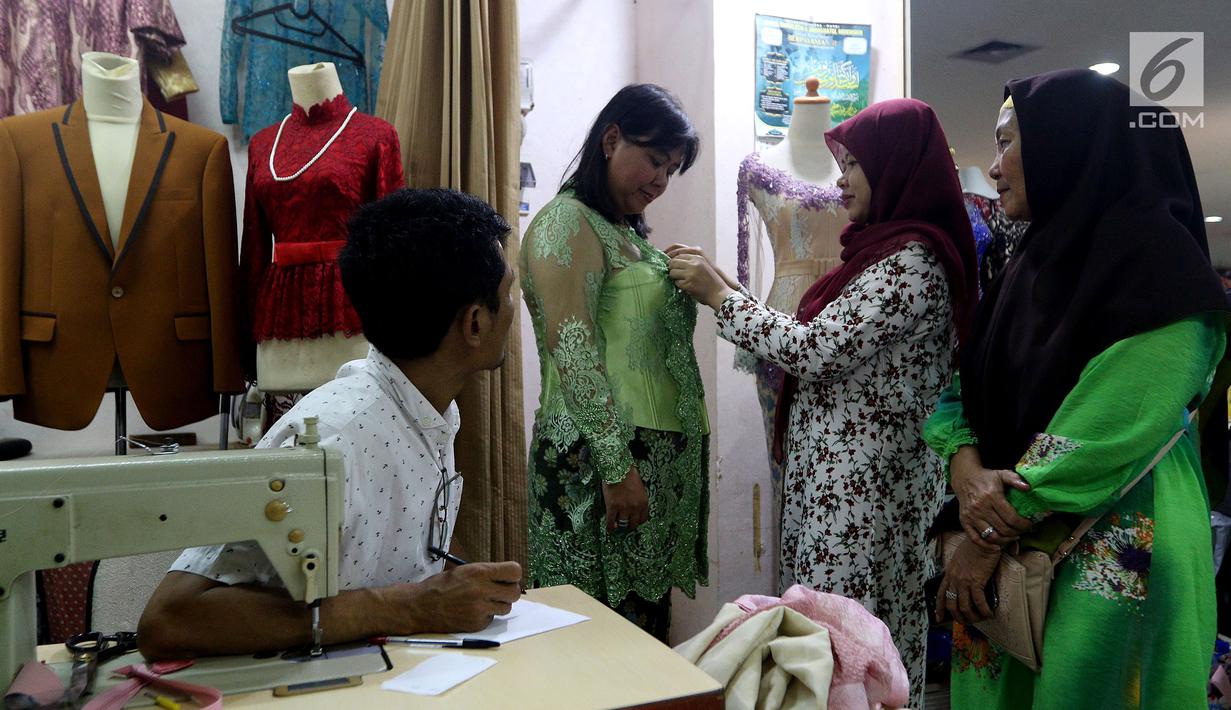 Pelanggan mencoba baju pesanannya yang dijahit di Pasar Mayestik, Jakarta Selatan, Senin (11/6). Masyarakat mulai membeli dan membuat baju pilihan mereka jelang Lebaran. (Liputan6.com/JohanTallo)
