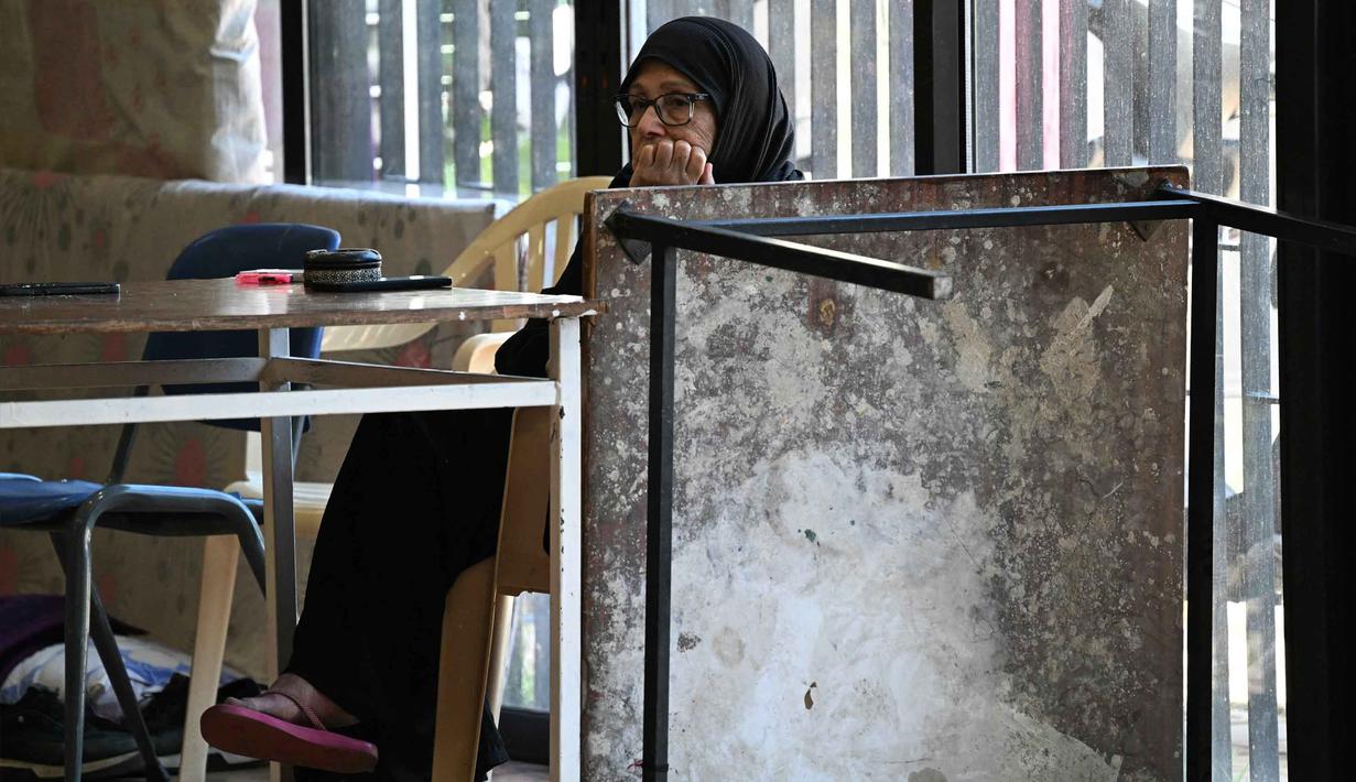 Kota-kota di sekitar Beirut seperti Dekwaneh menjadi tujuan utama karena dianggap relatif lebih aman dibandingkan wilayah selatan. Tampak dalam foto, seorang wanita duduk di dalam sebuah sekolah yang diubah menjadi tempat penampungan bagi para pengungsi di kota Dekwaneh, utara Beirut, Lebanon, pada Kamis 5 Maret 2026. (Joseph EID/AFP)