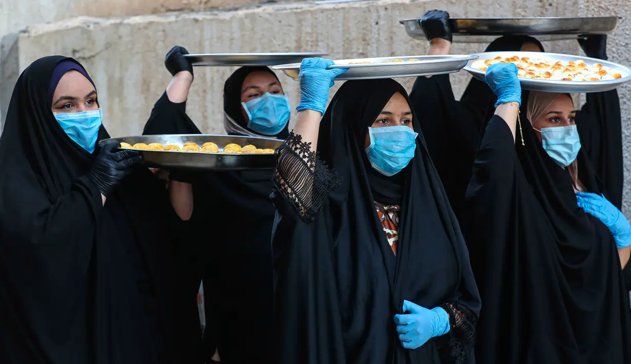 Sejumlah perempuan mengenakan masker untuk melindungi diri dari paparan virus corona COVID-19 saat membawa kue untuk perayaan Idul Fitri yang akan datang di Basra, Irak, Jumat (22/5/2020). Idul Fitri menandai berakhirnya bulan suci Ramadan. (AP Photo/Nabil al-Jurani)