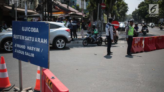 Petugas mengatur lalu lintas saat uji coba sistem satu arah (SSA) di Jalan KH Wahid Hasyim, Jakarta, Selasa (9/10). Penetapan SSA itu diharapkan dapat mengurangi parkir liar dan PKL yang kerap menutupi trotoar dan badan jalan. (Liputan6.com/Faizal Fanani)